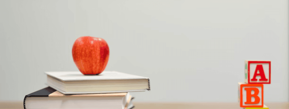 a red apple on top of a stack of books