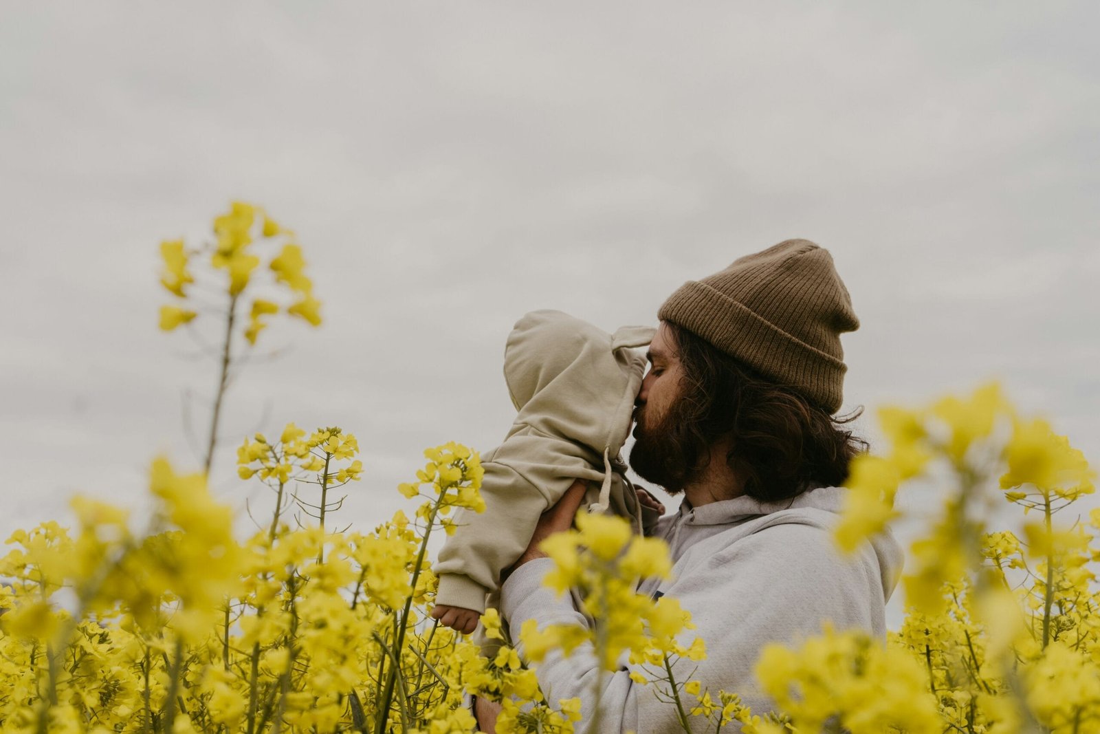 a man kissing a baby in a field of yellow flowers
