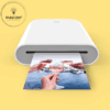 a white printer with hands holding a picture
